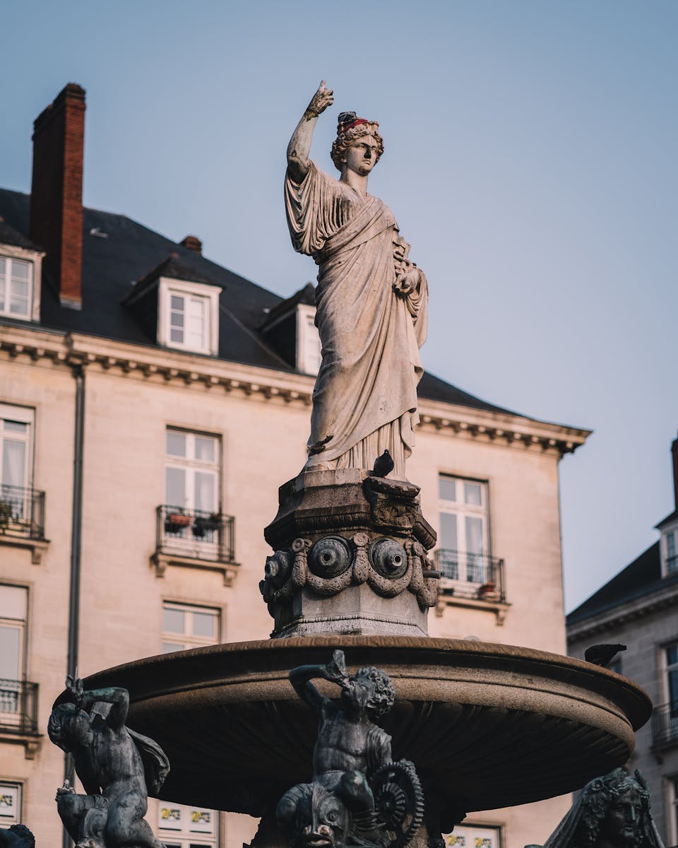 BRETAÑA FRANCESA: 1 al 5 de Abril 2 Elegant stone statue atop a fountain in a historic urban setting, showcasing classical architecture.